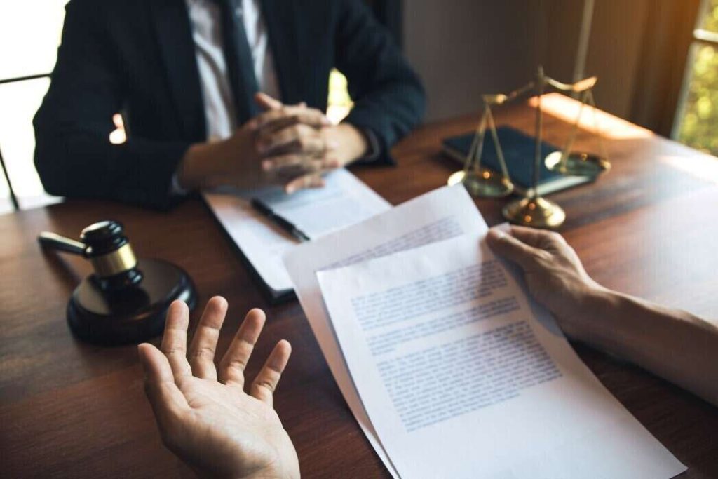 Entretien juridique avec documents, marteau de juge et balance de la justice, illustrant les règles de la légitime défense en droit français.